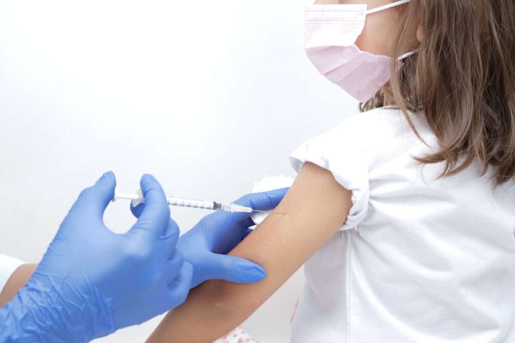 Vacina para criança medico com luva azul segurando seringa com agulha.