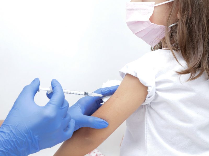 Vacina para criança medico com luva azul segurando seringa com agulha.